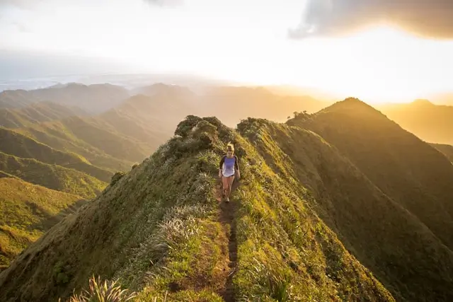 mujer bajo por el sendero de una montaña