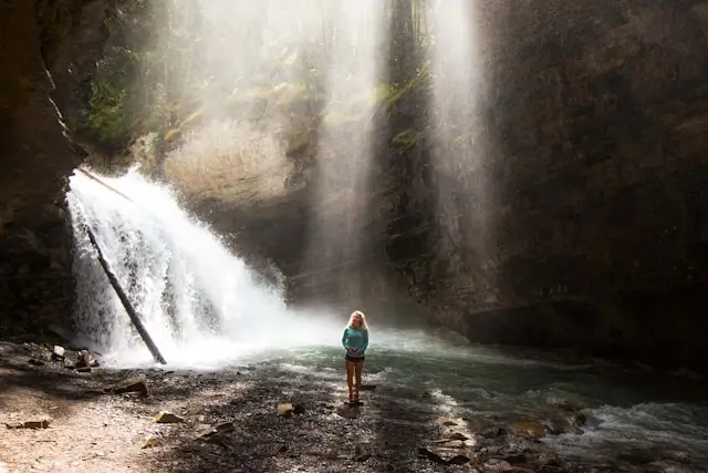 Chica dentro de una cueva admirando una cascada