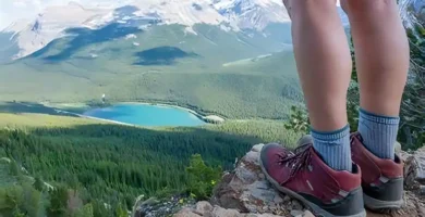 mujer con zapatillas de trekking admirando un lago a lo lejos