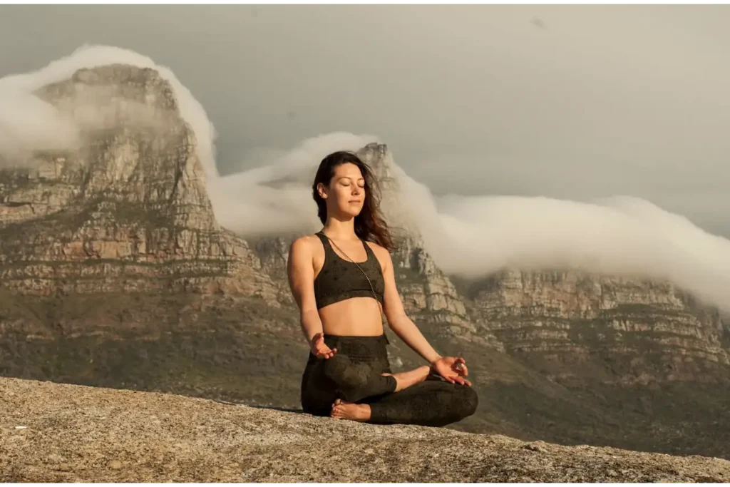 mujer meditando en la cima de una montaña